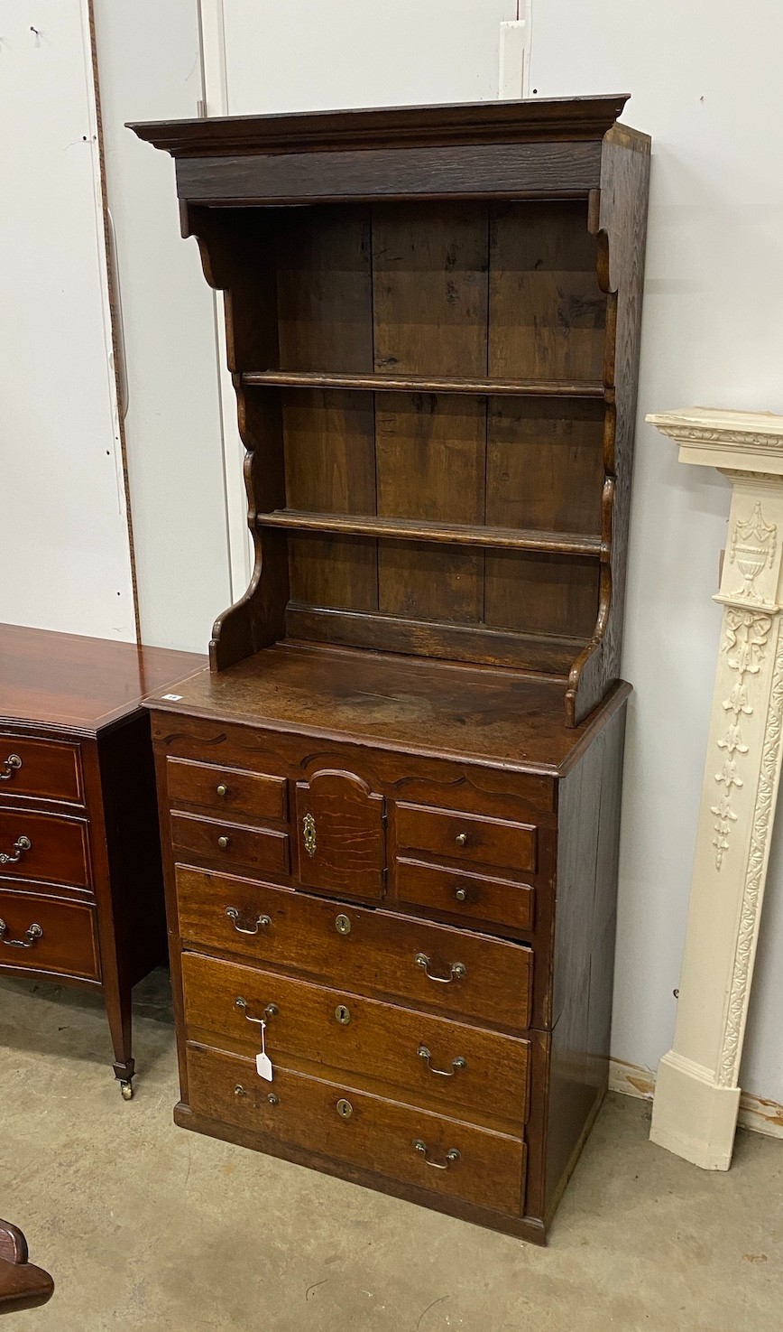 An 18th century oak chest of drawers with later associated oak shelves, width 79cm, depth 46cm, height 188cm